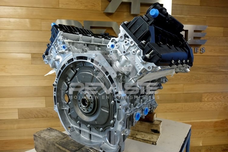Gedemonteerde automotor Land Rover op een houten ondergrond, met zicht op cilinderblok en transmissiebehuizing.